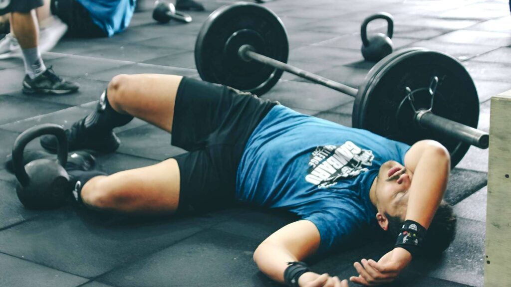 Man lying on the gym floor exhausted. | How To Stay Consistent with Exercise